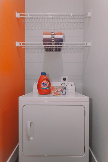 a small bathroom with a washer and dryer and a shelf above a toilet